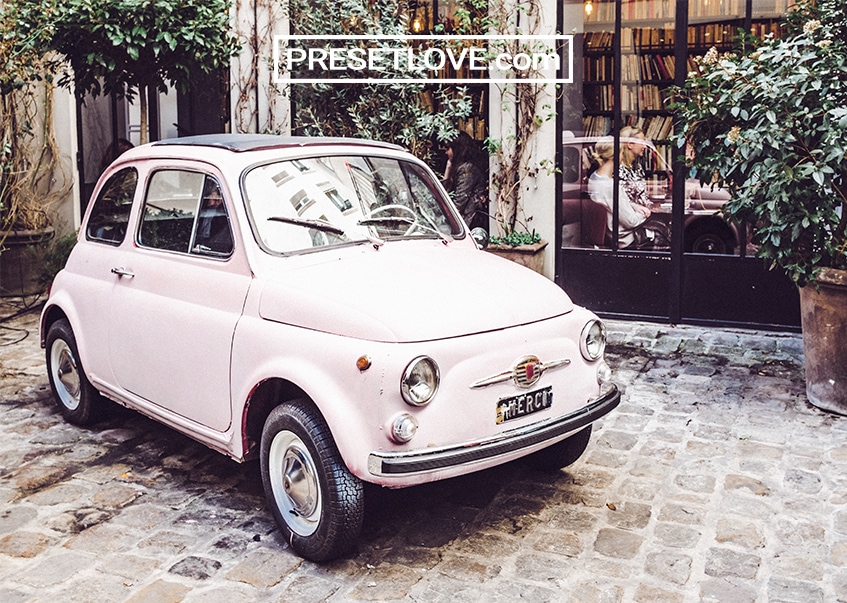 A vintage car on a road paved with cobble stones