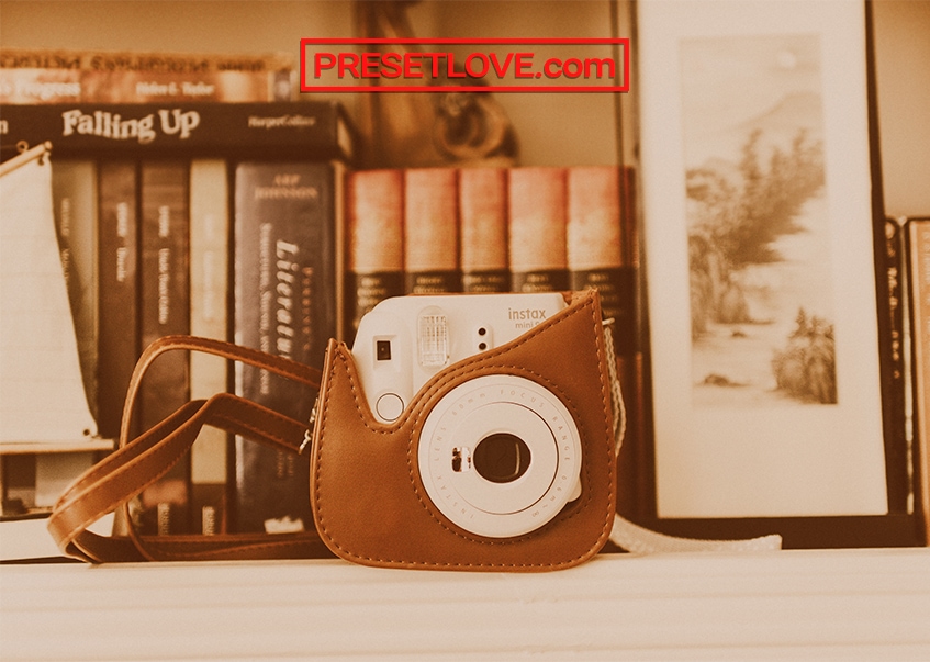 A orange-brown photo of an instant camera on a white desk