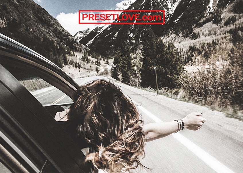 A cinematic image of a woman leaning out the car window with her arm outstretched