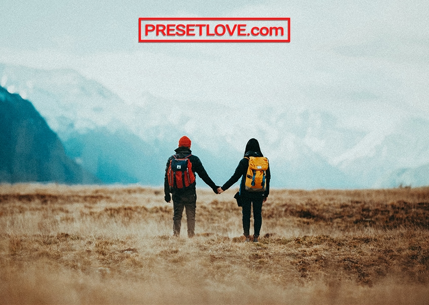 A couple holding hands and looking at the mountain landscape view