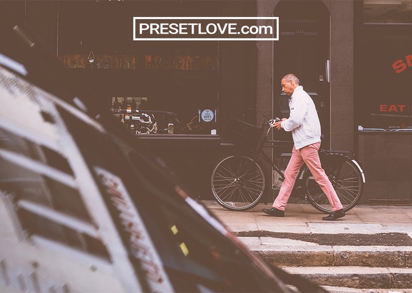 A matte vintage photo of a man rolling a bicycle beside him