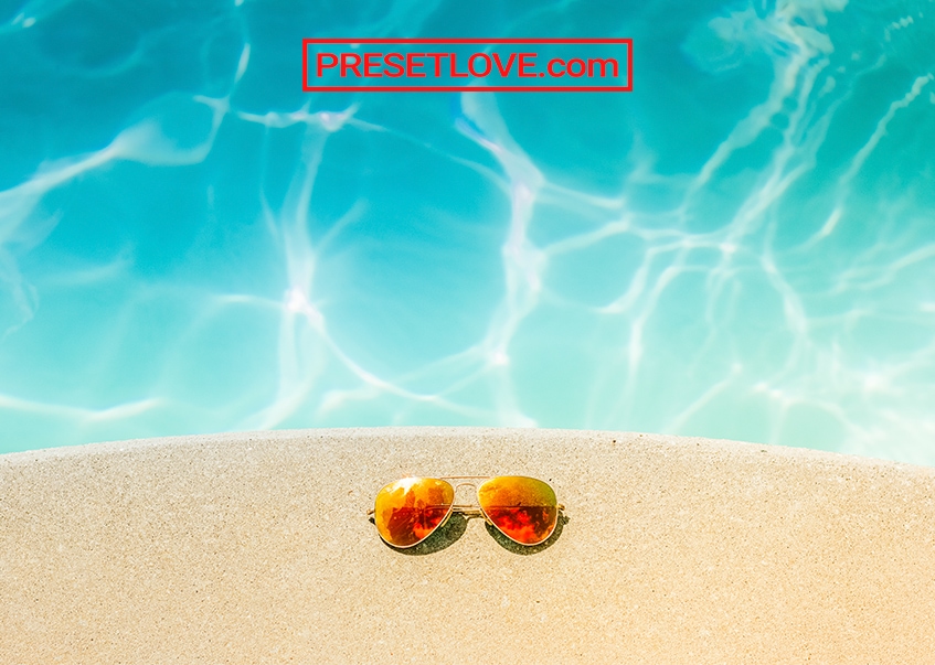 Photo of orange sunglasses on the sand, enhanced with Vibrant preset for Lightroom