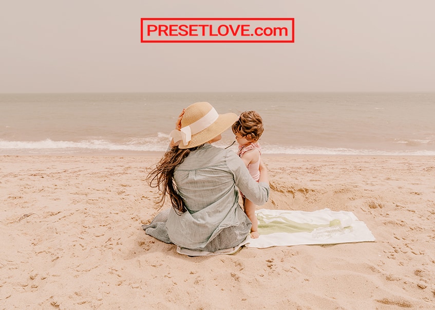 Photo of a mother and child at a beach, with a warm pastel Lightroom preset applied