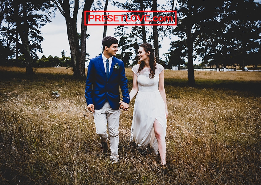 A vignetted photo of a bride and groom strolling in a field