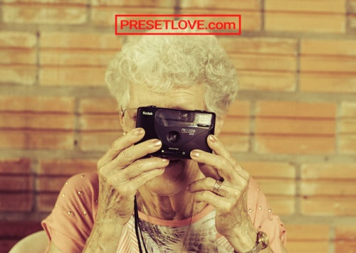 A retro shot of an old lady taking a photo using a film camera