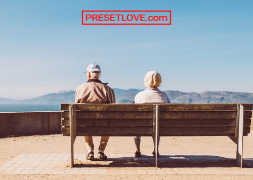 An old couple on a bench facing a landscape
