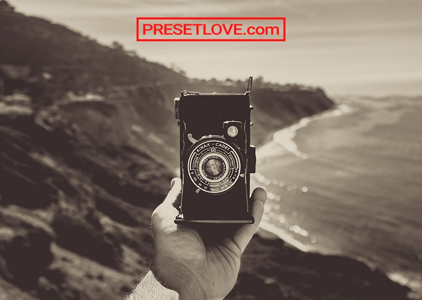 A hand holding up a vintage camera