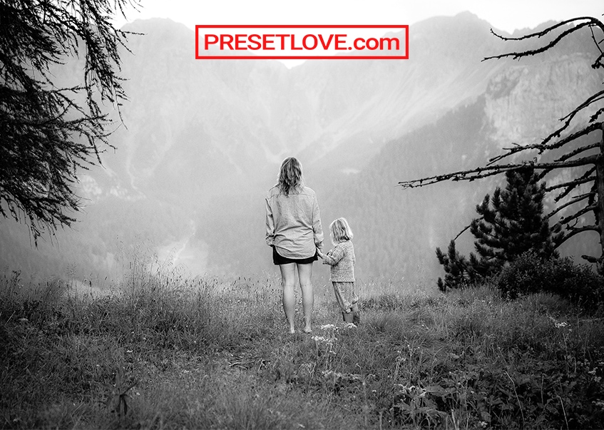 A black and white photo of a mother and child looking out into the landscape