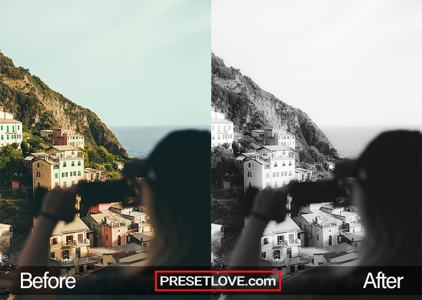 A smooth black and white photo of a woman taking a photo of a coastal town