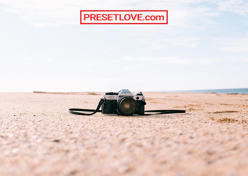 An analog camera on the sand by the beach