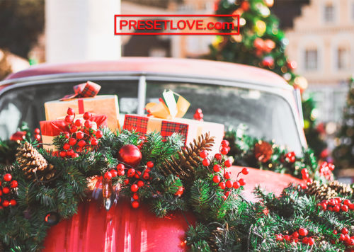 An ornate Christmas wreath on a red car's hood
